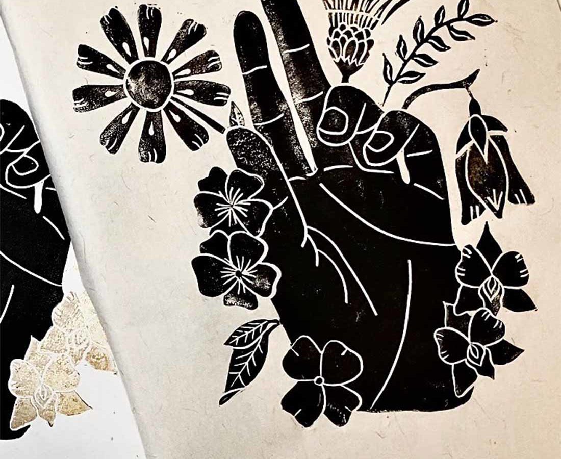 A stamped art in the shape of a hand holding flora.