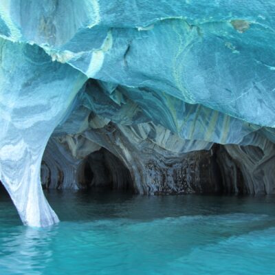 Glacier ice melts at the sea edge and forms cave formations as it melts.