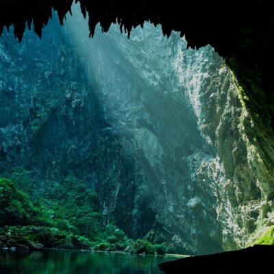 A large tropical cave with light shining into the entrance.