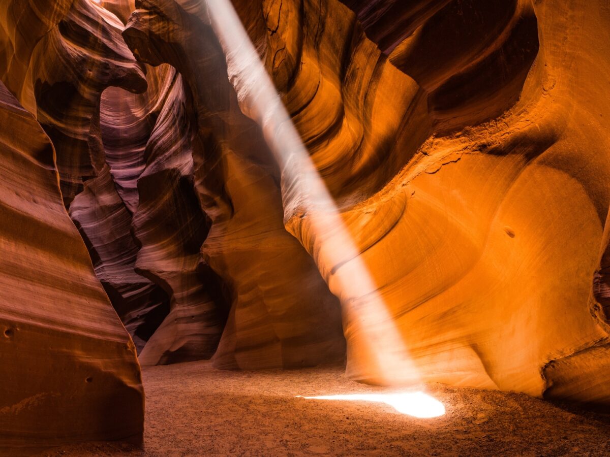 A beam of light shines into a sandstone canyon.