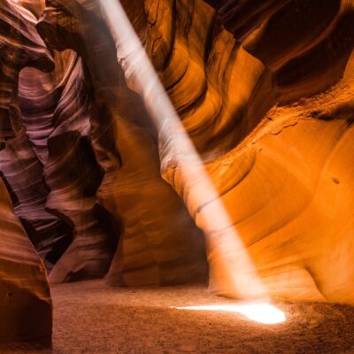 A beam of light shines into a sandstone canyon.