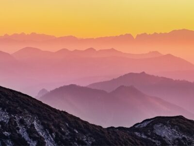 Distant mountains glow with pink and orange from a rising sun.
